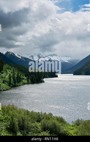 View at Duffey Lake, with overcast sky above snow covered mountains, surrounded by forest, along Highway 99, near Whistler, British Columbia, Canada Stock Photo