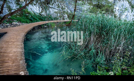 Empty and Lonely Path next to turquoise Water within the Plitvice Lakes National Park in Croatia Stock Photo