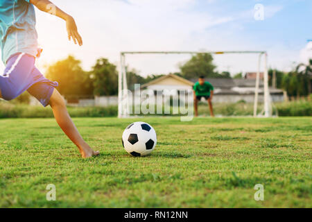 action sport outdoors of a group of kids having fun playing soccer football for exercise in community rural area under the twilight sunset sky. Stock Photo
