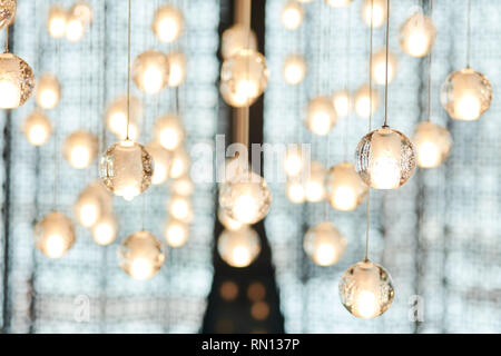 Silver crystal small balls hanging from ceiling as interior decoration over sky-blue background. Stock Photo