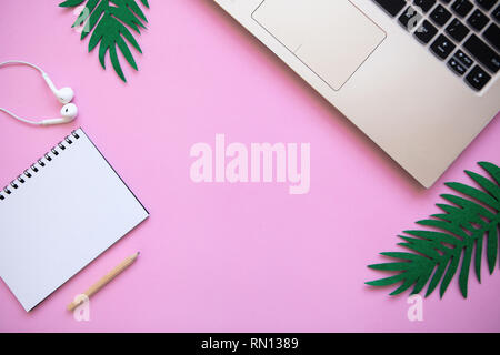 Workspace in a pink trendy color or summer design with a concept to start a vacation. Laptop and various things nearby. Stock Photo