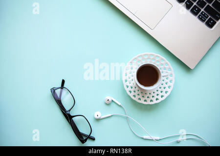 Workspace in a trendy blue color. Many different things including a laptop and headphones are on the table. Stock Photo