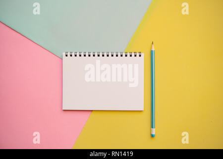 Blank notepad with place for text and a pencil on a multi-colored background. Stock Photo