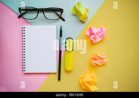 Blank notepad for text, glasses and other items on a multi-colored background. Stock Photo