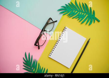 Notepad, glasses and a pencil on a multi-colored background. Stock Photo