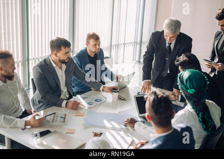 Collaborative process of multicultural professional financial or marketing managers during brainstorming meeting in office, headed by mature Senior He Stock Photo