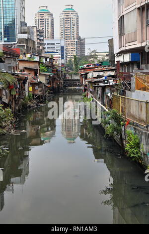 N-wards view from Soler Street bridge to the shack crowded banks of the Estero de San Lazaro channel of the Pasig river-Broadview Towers on background Stock Photo