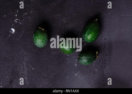 Tropical fruit, raw organic green feijoa on a dark black background, copy space. Healthy food concept Stock Photo