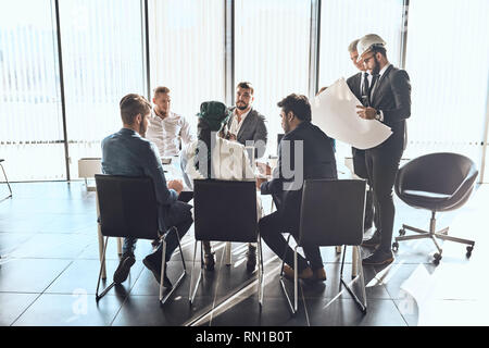 young active engineer is presenting his plan to office workers. building indusctry. trade concept Stock Photo