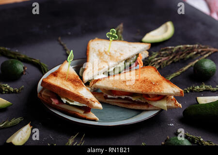 Sliced fruits and vegetables with warm tasty sandwiches on a black background. Healthy Breakfast, proper nutrition diet food concept Stock Photo