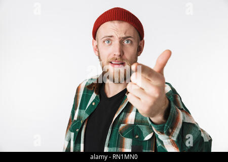 Portrait of satisfied bearded guy wearing hat and plaid shirt showing thumb up while standing isolated over white background Stock Photo