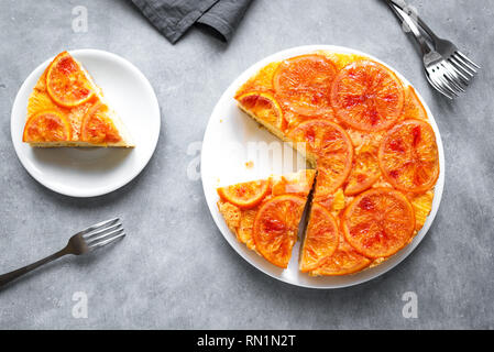 Upside down orange cake on grey background, copy space. Homemade cake with bloody oranges, citrus fruits. Stock Photo