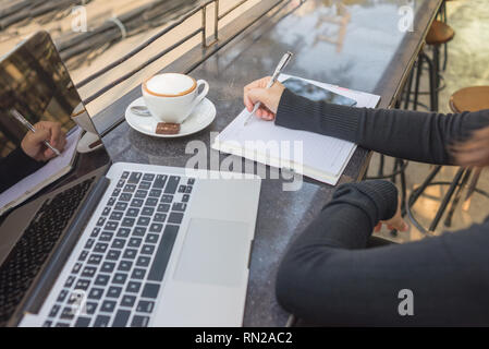 Side view of Asian student writing notes outdoor the Stock Photo