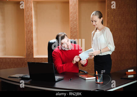 Confident boss with paper explaining something to secretary in the
