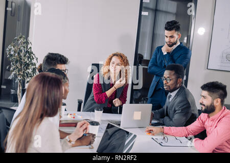 Multiracial team of young diverse employees sharing business ideas how to increase the company income, being involved in brainstorming activity Stock Photo