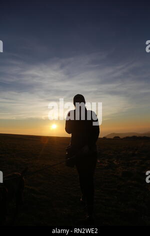 Woman in silhouette at sunset at Beachy Head cliffs Stock Photo