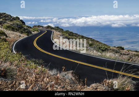 Maui Mountain Road:  The road from the top of Mt. Haleakalā begins above the clouds and descends to a tropical valley below. Stock Photo