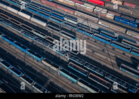 Aerial view of colorful freight trains on the railway station. Wagons with goods on railroad. Heavy industry. Industrial conceptual scene with trains. Stock Photo