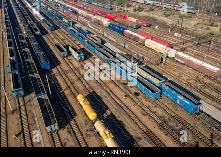 Aerial view of colorful freight trains on the railway station. Wagons with goods on railroad. Heavy industry. Industrial conceptual scene with trains. Stock Photo