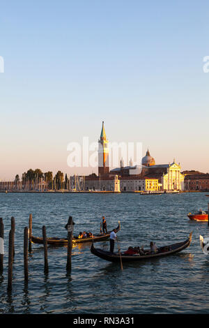 Gondolas on the lagoon in Basino San Marco at sunset, Venice, Veneto, Italy with the island of San Giorgio Maggiore behind at golden hour Stock Photo