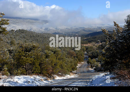 Gravel road disappears into the Sandia Mountains near Albuquerque, New Mexico.  Early morning clouds and fog hang close to mountain tops. Stock Photo