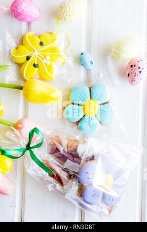 yellow tulips, ginger cookies, willow twigs, decorative eggs in a tray laid out on a white old wooden table, easter holiday background with sweets, fl Stock Photo