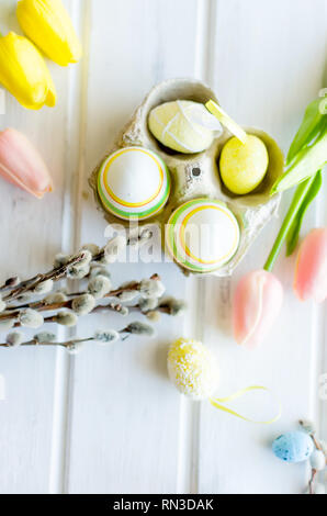 yellow tulips, ginger cookies, willow twigs, decorative eggs in a tray laid out on a white old wooden table, easter holiday background with sweets, fl Stock Photo