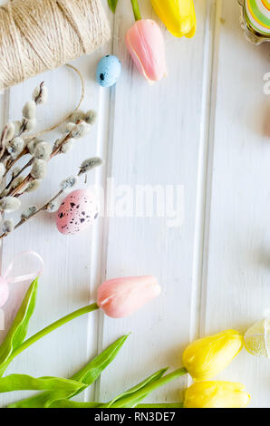 yellow tulips, ginger cookies, willow twigs, decorative eggs in a tray laid out on a white old wooden table, easter holiday background with sweets, fl Stock Photo
