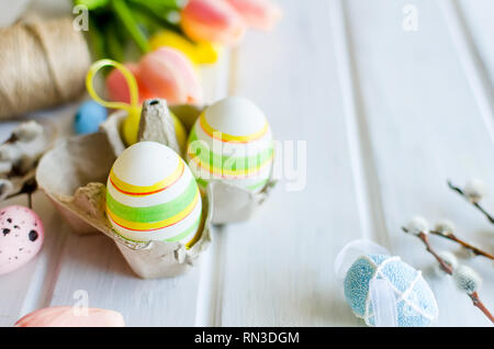 yellow tulips, ginger cookies, willow twigs, decorative eggs in a tray laid out on a white old wooden table, easter holiday background with sweets, fl Stock Photo