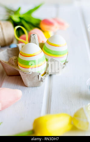 yellow tulips, ginger cookies, willow twigs, decorative eggs in a tray laid out on a white old wooden table, easter holiday background with sweets, fl Stock Photo