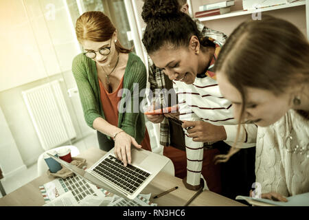 Student wearing glasses holding laptop showing information Stock Photo