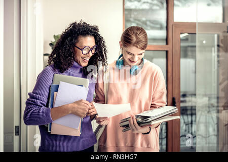 Helpful curly dark-haired student helping her friend with math Stock Photo