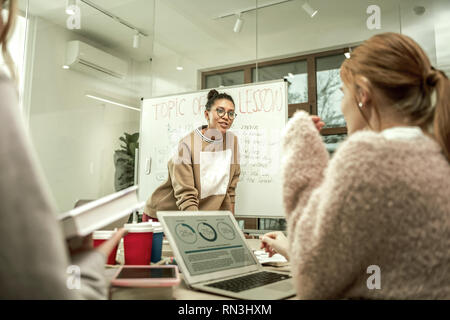 Red-haired student wearing pink sweater presenting her project Stock Photo