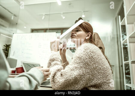 Red-haired student wearing pink sweater feeling shocked after test Stock Photo