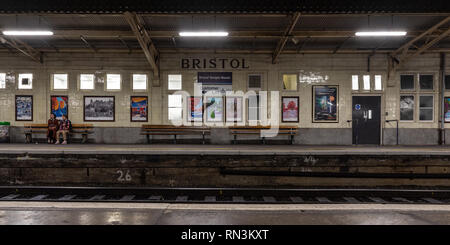 Bristol, England, UK - January 12, 2019: A commuter couple sit on a platform bench waiting for a train at Bristol's Temple Meads railway station. Stock Photo