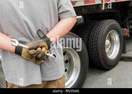 Man's hands behind his back holding wrench Stock Photo