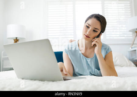 Young woman using laptop on bed Stock Photo