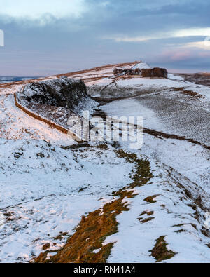 Winter snow lies on Hadrian's Wall path as it crosses the Peel Crags and Green Slack at Once Brewed in Northumberland. Stock Photo