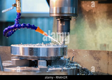 Drilling machine makes a hole in the metal product. Coolant is pouring on the drill. Stock Photo