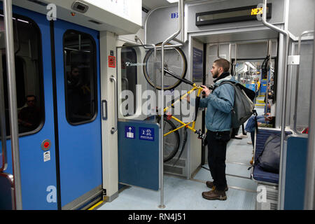 A Seattle bicyclist stows a bicycle at a designated holding area inside a Sound Transit Link light rail car Stock Photo