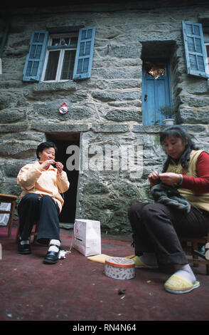 Caption: Lushan, Hefei, China - Nov 2002. Women knitting outside their house in the old European hill station of Lushan, a small town above the Yangtz Stock Photo