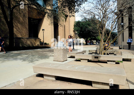 Cement benches on the campus of Texas A&M University in College Station, Texas, USA; student walking; smile written in cursive with chalk on a bench. Stock Photo