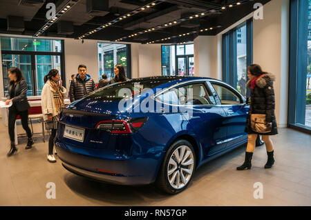 Chinese customers looking over a blue Tesla Model 3 on display in the Taikoo Hui branch of Tesla near Shanghai’s Nanjing Road. Stock Photo