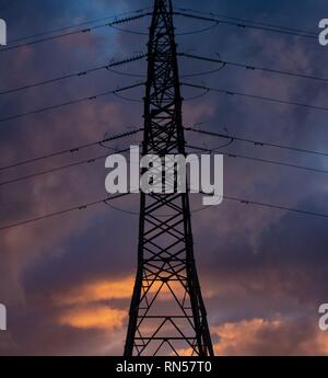 electricity pylon silhouetted at sunset Stock Photo