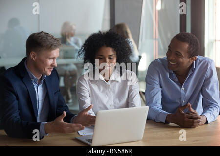 Three workmates sitting at desk working together using laptop Stock Photo