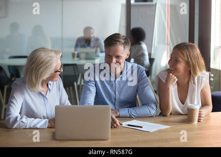 Employees sitting in coworking space working together using laptop Stock Photo