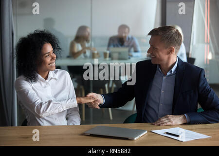 Happy diverse millennial workers starting meeting with handshaking Stock Photo