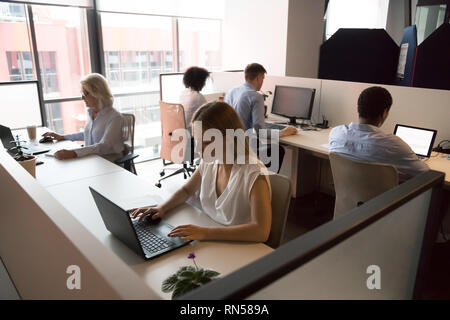 Employees working in coworking office sitting at desk using computers Stock Photo