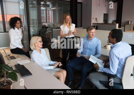 Positive friendly coworkers communicating in shared office Stock Photo