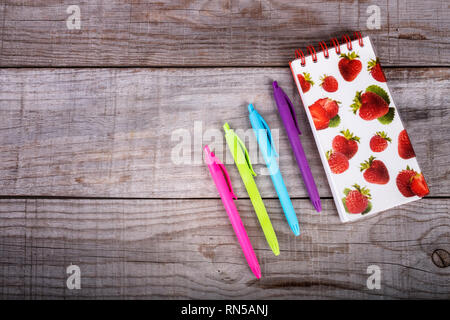notepad and set of colored pens on wooden background Stock Photo